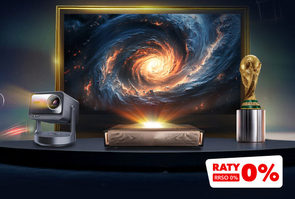 Na zdjęciu znajduje się projektor, urządzenie elektroniczne oraz statuetka przypominająca puchar, ustawione na ciemnym tle z dynamiczną grafiką przedstawiającą wirującą galaktykę. W prawym dolnym rogu widnieje czerwony napis RATY RRSO 0%.