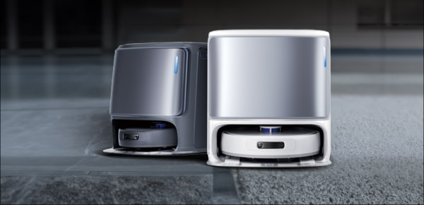 Dwa roboty sprz?taj?ce w stacjach dokuj?cych, jeden w ciemniejszej, a drugi w ja?niejszej obudowie. Oba urz?dzenia stoj? na pod?odze, a ich konstrukcja jest nowoczesna i minimalistyczna.